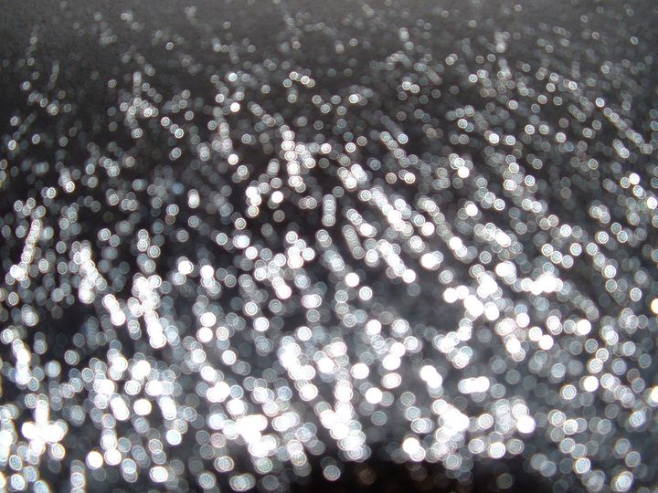 illuminated, out-of-focus raindrops on a glass surface