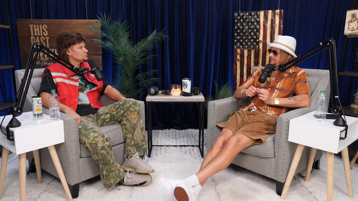 Theo Von and Kid Rock sitting across from each other on armchairs in Von's podcast studio.
