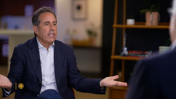 Jerry Seinfeld sitting in a chair during an interview with CBS.